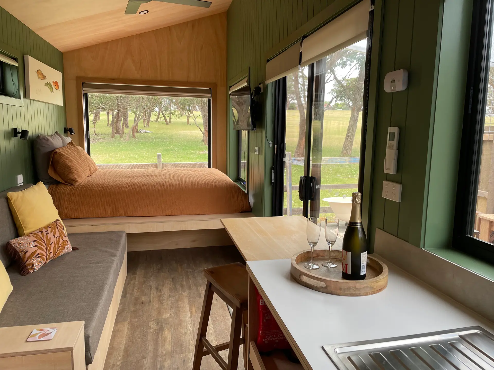 Inside The Hideaway tiny house: bed, day bed and champagne on the bench